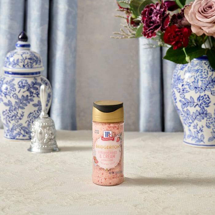 A container of Stonewall Kitchen Strawberry Lemonade Sugar stands on a table with decorative vases and flowers.