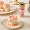 A close-up shows mini cakes decorated with pink frosting and McCormick Rose Flavor Sugar Sprinkles.