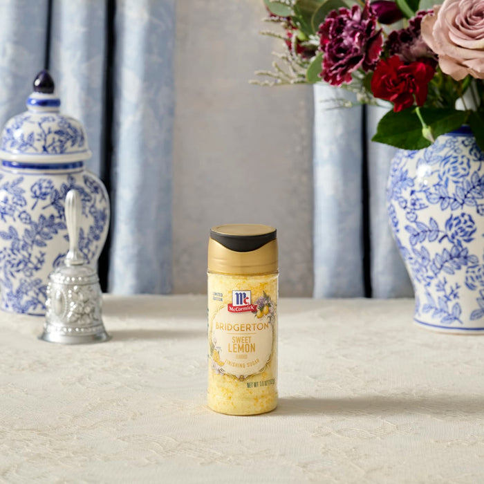 A container of McCormick Lemon &amp; Herb Seasoning stands on a table with decorative blue and white accents.