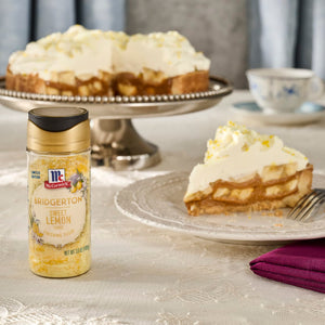 A slice of banana cream pie and the whole pie are displayed with a bottle of McCormick Imitation Lemon Extract.