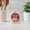 A packet of McCormick Creamy Tuscan Chicken &amp; Pasta mix stands on a kitchen counter.