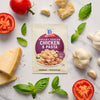 A packet of McCormick Creamy Tuscan Chicken &amp; Pasta mix is surrounded by fresh ingredients like tomatoes, garlic, basil, and parmesan cheese.