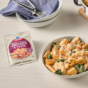 A bowl of creamy chicken and pasta made with McCormick Creamy Chicken &amp; Pasta seasoning mix is displayed next to the seasoning packet.