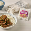 A bowl of rice topped with beef stir-fry next to a McCormick Beef &amp; Broccoli Stir-Fry seasoning packet.