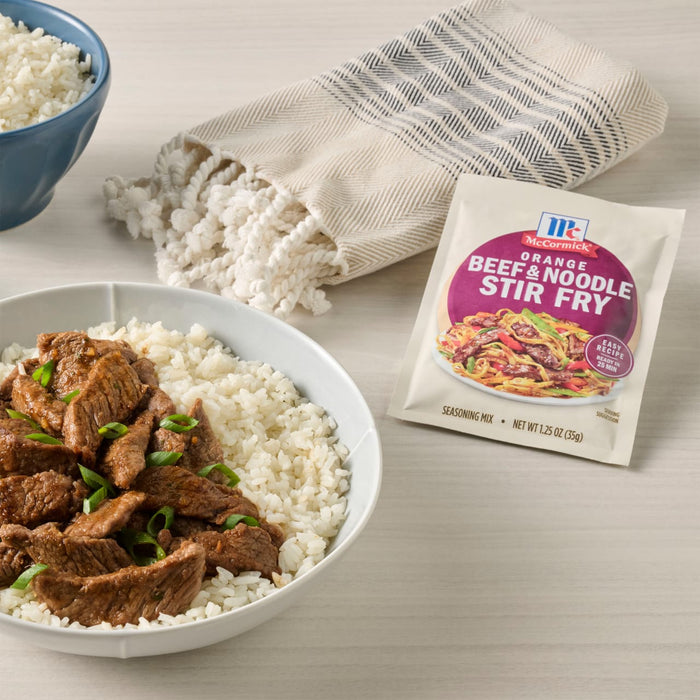 A bowl of rice topped with beef stir-fry next to a McCormick Beef &amp; Broccoli Stir-Fry seasoning packet.