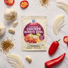 A packet of McCormick Chicken Burrito Bowl seasoning mix is surrounded by fresh ingredients like garlic, onions, and peppers.