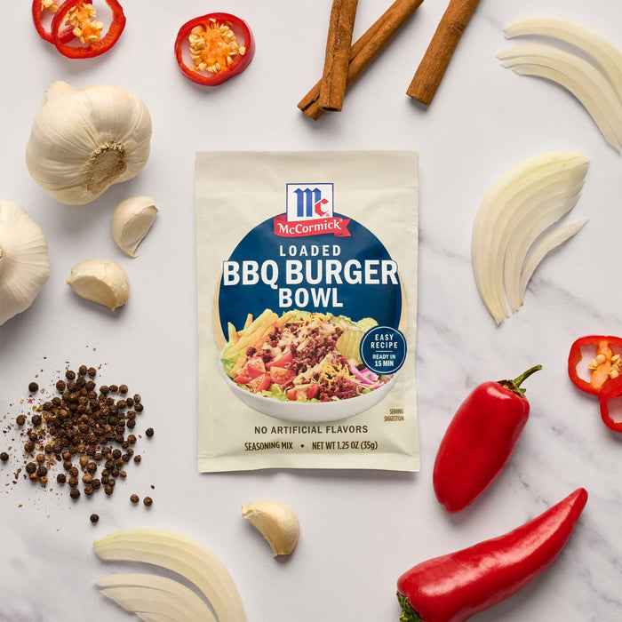 A packet of McCormick BBQ Burger Bowl seasoning mix is surrounded by fresh ingredients like garlic, onions, and peppers.