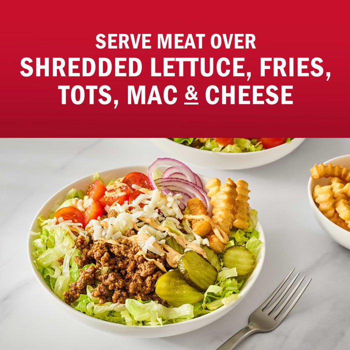 A bowl of shredded lettuce topped with meat, tomatoes, cheese, red onion, pickles, and fries, suggesting various ways to serve meat.