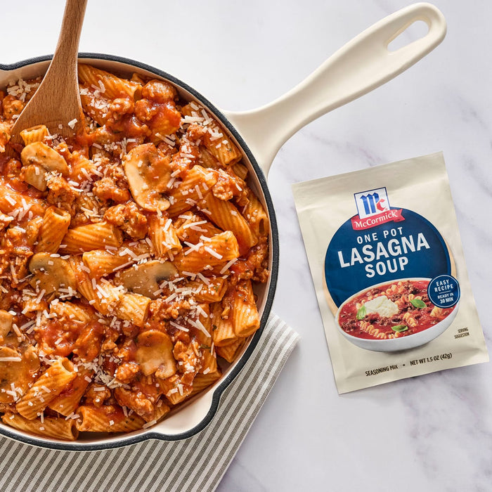 A skillet of lasagna soup with a wooden spoon and a packet of McCormick Lasagna Soup Mix.