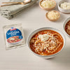 A packet of Taste of Home Lasagna Soup mix is displayed next to a bowl of the prepared soup, garnished with cheese and ricotta.