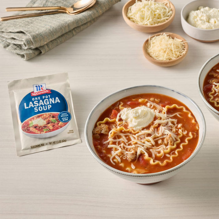 A packet of Taste of Home Lasagna Soup mix is displayed next to a bowl of the prepared soup, garnished with cheese and ricotta.