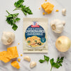 A packet of McCormick's Cheesy Chicken and Rice Casserole mix is surrounded by fresh ingredients like cheese, garlic, onion, and parsley.