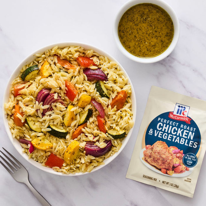 A bowl of rice and vegetables with McCormick's Roasted Chicken &amp; Vegetables seasoning packet and a small bowl of sauce.