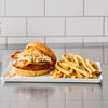 A delicious chicken sandwich with crispy fries on a white plate.