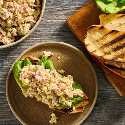 A top-down view of a tuna salad sandwich prepared with Mccormick Grill Mates Buttermilk Dill Pickle Seasoning Mix, 1.0 Oz on grilled bread with lettuce and red onion.
