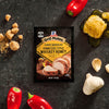 A packet of Mccormick Grill Mates Tennessee Style Whiskey Honey Marinade Seasoning Mix, 1.0 Oz is displayed on a dark textured surface surrounded by fresh ingredients like red peppers, garlic cloves, honeycomb, and brown sugar cubes.