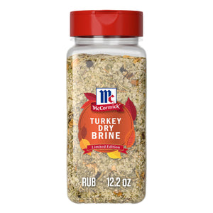 A clear plastic bottle with a red flip-top lid contains Mccormick Turkey Dry Brine Rub, 12.2 Oz, featuring a blend of coarse salt and herbs visible through the container.