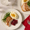 A top down view of two plates featuring sliced turkey seasoned with Mccormick Turkey Dry Brine Rub, 12.2 Oz alongside mashed potatoes with gravy, green beans, and cranberry sauce.