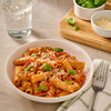 A delicious bowl of rigatoni pasta in a creamy red sauce made with Mccormick Spicy Vodka Sauce Seasoning Mix, 1.0 Oz, is garnished with fresh basil and grated cheese.