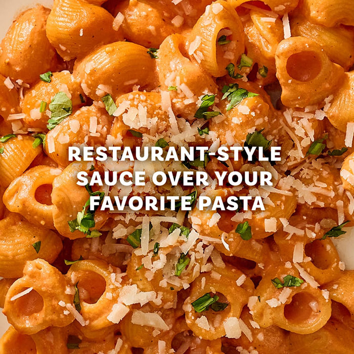 A close-up of shell pasta in a creamy pink sauce, garnished with cheese and herbs, shows a delicious meal you can create with Mccormick Spicy Vodka Sauce Seasoning Mix, 1.0 Oz.