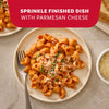 A finished plate of pasta made with Mccormick Spicy Vodka Sauce Seasoning Mix, 1.0 Oz, is garnished with freshly grated Parmesan cheese and parsley, with a fork resting on the plate.