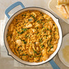 A delicious one-pan meal of creamy chicken and orzo, prepared using Mccormick Marry Me Chicken Seasoning Mix, 0.75 Oz, is presented in a light blue skillet next to a side of bread.