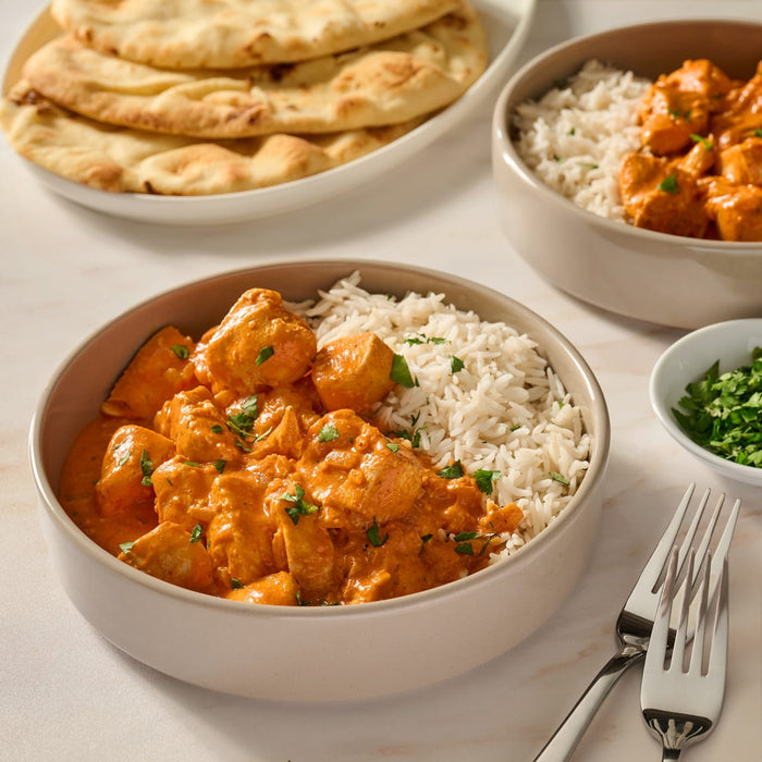 A delicious bowl of chicken tikka masala and rice, prepared using Mccormick Chicken Tikka Masala Seasoning Mix, 0.87 Oz, is served with naan bread.