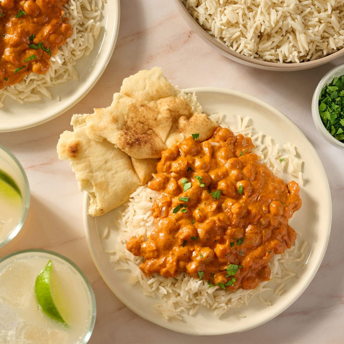 A delicious-looking plate of chicken tikka masala, prepared using Mccormick Chicken Tikka Masala Seasoning Mix, 0.87 Oz, is served over a bed of white rice with a side of naan bread.