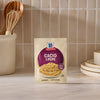 A packet of Mccormick Cacio E Pepe Seasoning Mix, 1.12 Oz, is displayed on a kitchen countertop in front of a tiled backsplash, with kitchen utensils and plates in the background.
