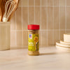 A bottle of Mccormick Garlic And Olive Oil Seasoning Blend, 5.25 Oz, sits on a kitchen counter next to utensils and plates.