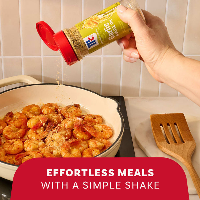 A hand seasons cooking shrimp in a pan with a shake of Mccormick Garlic And Olive Oil Seasoning Blend, 5.25 Oz, demonstrating an effortless meal.