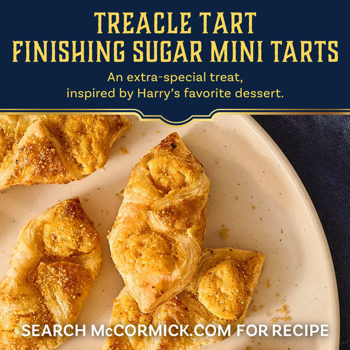 Several golden, flaky treacle tart mini tarts are shown on a white plate, finished with a generous sprinkle of Mccormick Harry Potter Treacle Tart Finishing Sugar, 3.43 Oz, in a promotional recipe image.
