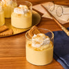 In a magical, Harry Potter-inspired setting, several glasses of creamy pudding are topped with whipped cream and a generous sprinkle of Mccormick Harry Potter Treacle Tart Finishing Sugar, 3.43 Oz.