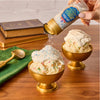 A hand sprinkles Mccormick Harry Potter Drooble'S Best Blowing Gum Finishing Sugar, 3.36 Oz onto a golden bowl of vanilla ice cream topped with whipped cream.