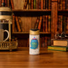 A bottle of Mccormick Harry Potter Drooble'S Best Blowing Gum Finishing Sugar, 3.36 Oz, sits on a wooden desk in a cozy library setting, complete with a French press, a mug, and round glasses resting on old books.