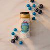 A top-down view shows a bottle of Mccormick Harry Potter Drooble'S Best Blowing Gum Finishing Sugar, 3.36 Oz, styled on a marble surface with fresh blueberries and blue gumballs.