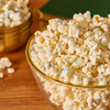 A glass bowl of white-coated popcorn is decorated with a sprinkle of Mccormick Harry Potter Drooble'S Best Blowing Gum Finishing Sugar, 3.36 Oz, creating a magical-looking snack.