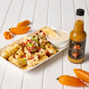 A plate of poutine with hot sauce and peppers, showcasing the brand's spicy flavor.
