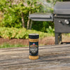 Two juicy cheeseburgers topped with caramelized onions and a generous amount of Mission Bbq Kc Classic Bold Barbecue Sauce Plastic Squeeze Bottle 16 Oz are served on a wooden board for a backyard meal.