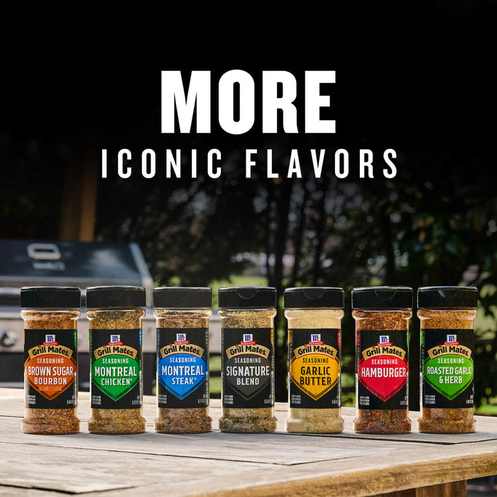 A lineup of McCormick Grill Mates seasonings, including Brown Sugar Bourbon, Montreal Chicken, and the Grill Mates Signature Blend Seasoning, 6.53 Oz Bottle, are displayed on a wooden table outdoors to showcase the brand's iconic flavors.
