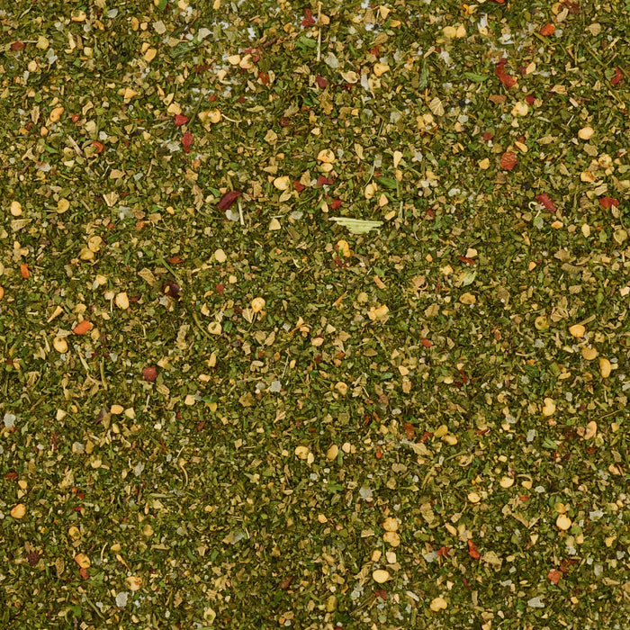 A close-up, top-down view reveals the vibrant texture of Mccormick Chimichurri Flavored Seasoning, 2.47 Oz, showing a mix of green herbs, red pepper flakes, and other spices.