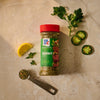 A bottle of Mccormick Chimichurri Flavored Seasoning, 2.47 Oz, is arranged on a marble surface with a measuring spoon of the seasoning and fresh ingredients like parsley, jalapeño, and lemon to suggest its flavor profile.