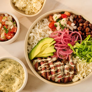 A vibrant steak burrito bowl is presented with steak seasoned using Mccormick Chimichurri Flavored Seasoning, 2.47 Oz, alongside rice, black beans, avocado, pico de gallo, and crumbled cheese.