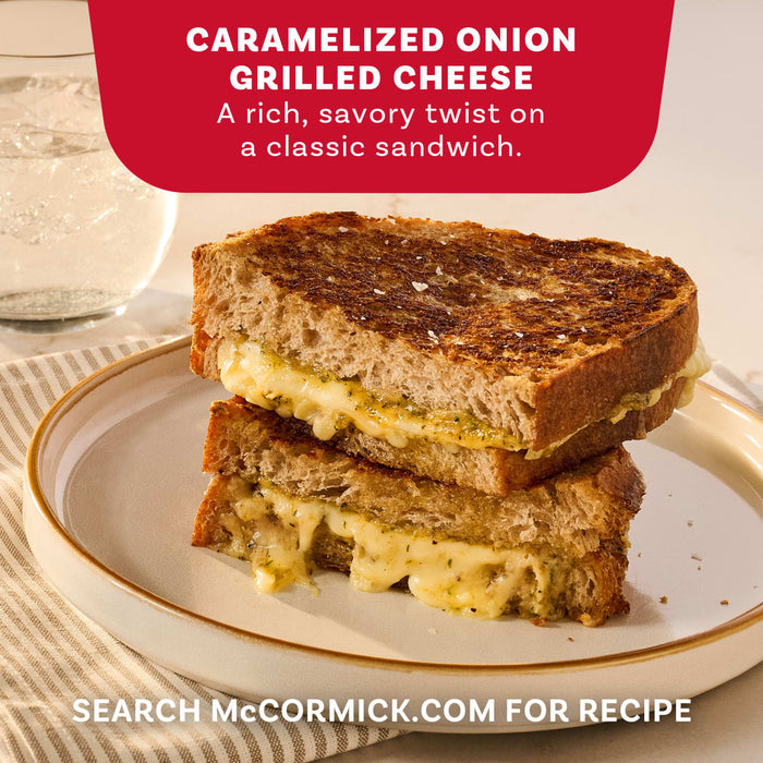 A perfectly toasted Caramelized Onion Grilled Cheese sandwich, a recipe idea using Mccormick Caramelized Onion Seasoning, 4.66 Oz, is cut in half and stacked on a plate to show the gooey melted cheese.