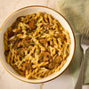 A savory bowl of gemelli pasta with mushrooms and melted cheese, seasoned with Mccormick Caramelized Onion Seasoning, 4.66 Oz, is ready to be eaten.