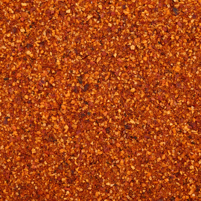 A detailed, top-down macro shot reveals the coarse texture and vibrant red and orange colors of Mccormick Chili Garlic Seasoning, 5.22 Oz.