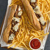 Two Philly cheesesteak sandwiches, with steak prepared using Mccormick Grill Mates Garlic Butter Seasoning, 6.56 Oz, are served on a bed of french fries with ketchup.