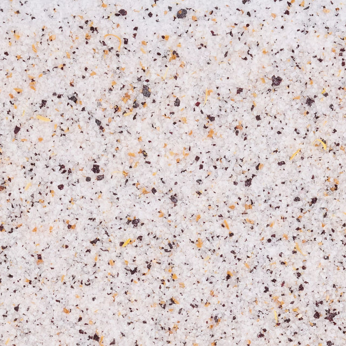 A close-up, top-down view shows the texture of Mccormick Blueberry And Lemon Finishing Sugar, 3.43 Oz, with its white sugar crystals mixed with dark specks of blueberry and yellow flecks of lemon.