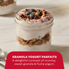 A glass jar holds a granola yogurt parfait topped with blueberries and a sprinkle of Mccormick Blueberry And Lemon Finishing Sugar, 3.43 Oz.