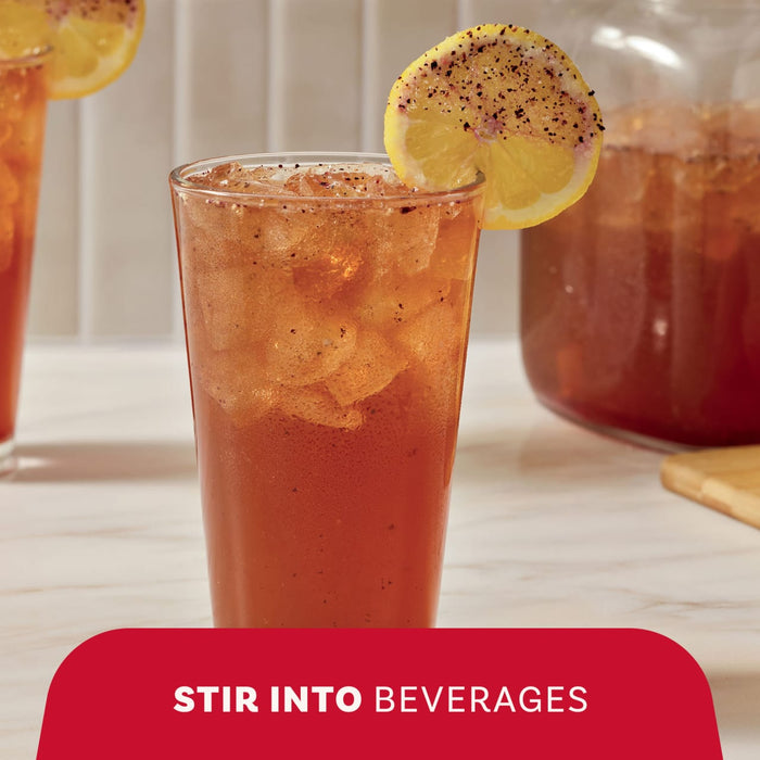 A refreshing glass of iced tea garnished with a lemon slice shows how Mccormick Blueberry And Lemon Finishing Sugar, 3.43 Oz can be stirred into beverages for added flavor.